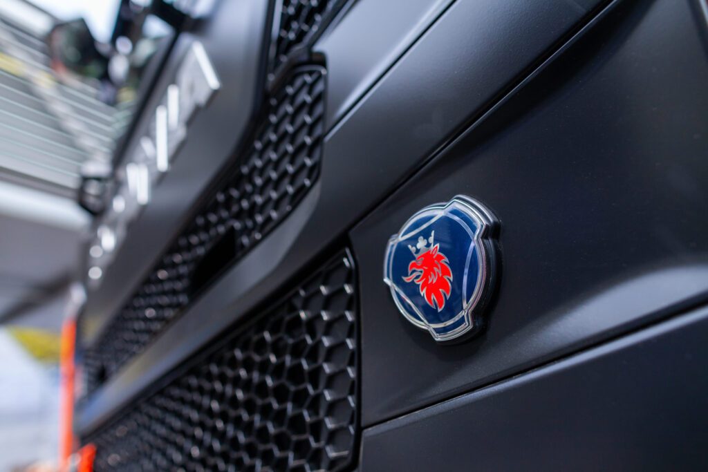 Close-up of a blue circular emblem with a red lion on the front of a dark truck hood/grille.