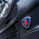 Close-up of a blue circular emblem with a red lion on the front of a dark truck hood/grille.