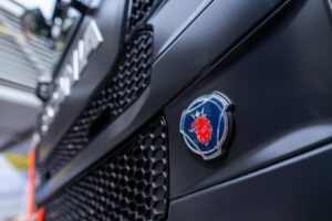 Close-up of a blue circular emblem with a red lion on the front of a dark truck hood/grille.